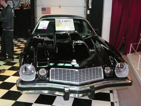 1997 Mercury Grand Marquis - A black coupe with a prominent hood scoop is displayed indoors on a checkered floor.