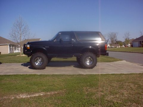 1995 Ford Bronco - Side view of a lifted black 1995 Ford Bronco on a sunny day.