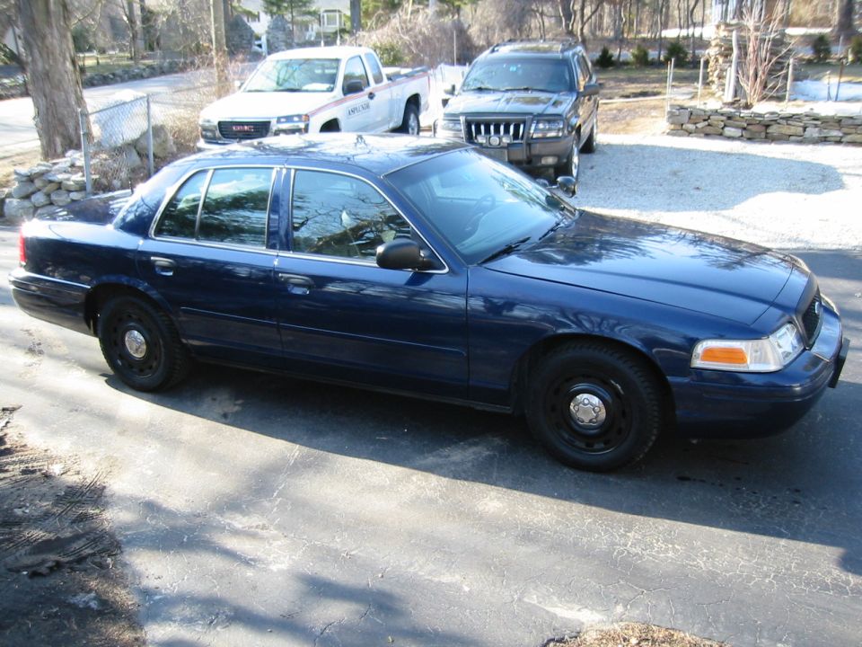 2003 Ford Crown Victoria parked on driveway with a white pickup and black SUV behind it