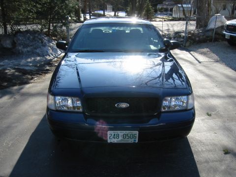 2003 Ford Crown Victoria - A blue Ford Crown Victoria is parked in a driveway on a sunny day.