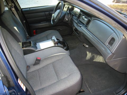 2003 Ford Crown Victoria - The interior of a Ford Crown Victoria is visible from the passenger side, showing the front seats and dashboard.