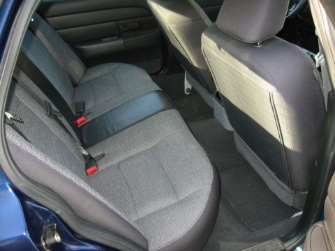 2003 Ford Crown Victoria - The rear interior of a 2003 Ford Crown Victoria shows gray fabric seats with black trim and red seatbelt buckles.