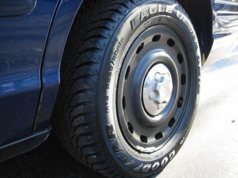 2003 Ford Crown Victoria - Close-up of a Goodyear Eagle Ultra Grip tire on a steel wheel with a Ford logo center cap.