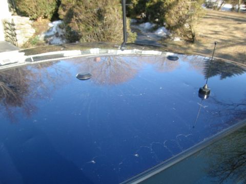 2003 Ford Crown Victoria - The top of a dark blue vehicle is visible, two circular mounts and a radio antenna.