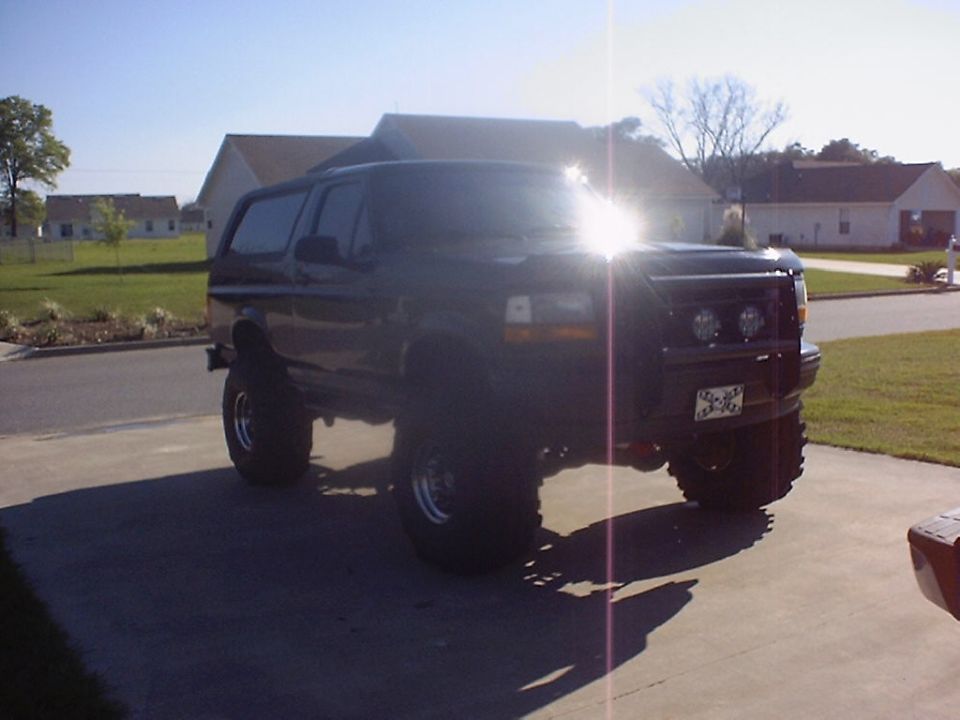 Black lifted Ford Bronco SUV on driveway with big tires and bumper lights