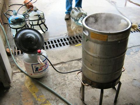 1985 Ford LTD Crown Victoria - A setup involving a keg, propane tank, and water jugs suggests a brewing or heating process.