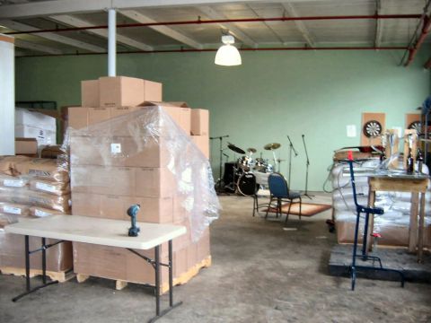 1985 Ford LTD Crown Victoria - An indoor scene shows a drum kit and microphones set up near stacked boxes and a folding table.