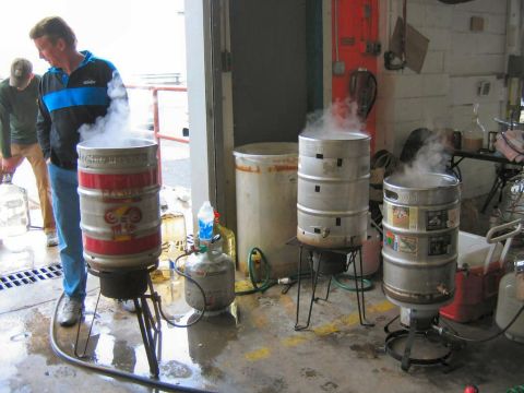 1985 Ford LTD Crown Victoria - Brewing equipment is set up in a garage, with three large kegs heating up and producing steam.