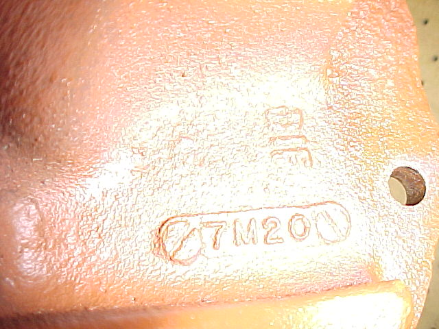 Close-up of a cast metal part showing casting numbers 7M200 and other markings