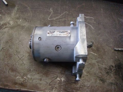 1996 Ford Bronco - A close-up view of a silver starter motor with a metal data plate attached.