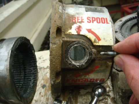 1996 Ford Bronco - Winch free spool mechanism with visible labels. A hand is adjusting a screw on the part.