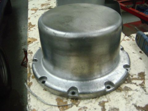 1996 Ford Bronco - Close-up of a metal hubcap or cover with visible bolt holes on a weathered surface.