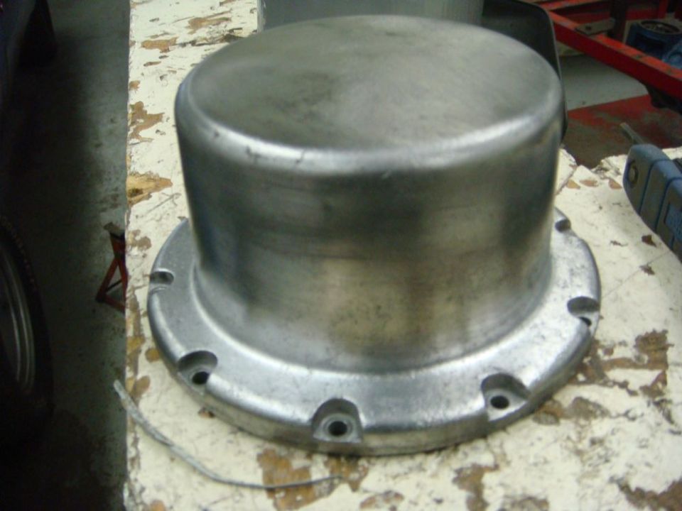 Metal hubcap or cover with bolt holes on a workbench