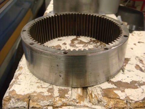 1996 Ford Bronco - A close-up view of a metal gear ring with internal teeth, resting on a distressed wooden surface.