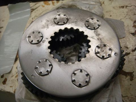 1996 Ford Bronco - Metal clutch housing with internal gears and six bolt covers visible.