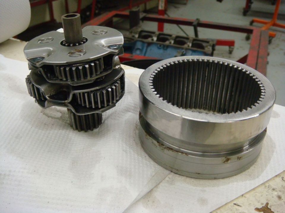 Gear set with multiple gears stacked on a shaft next to a cylindrical housing with internal splines