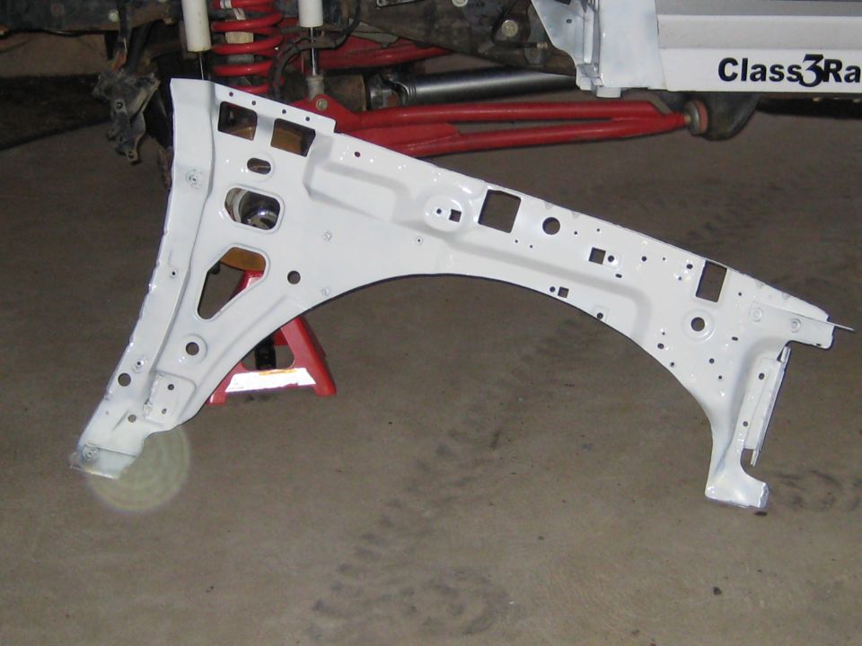 White-painted inner fender apron panel on a garage floor in front of a truck chassis