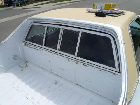 1975 Ford Ranchero - The rear window and bed of a 1975 Ford Ranchero are visible, with items stacked on the roof.