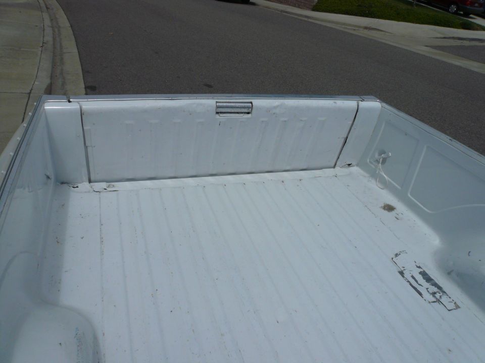 White pickup truck bed interior with ribbed floor and tie-down points