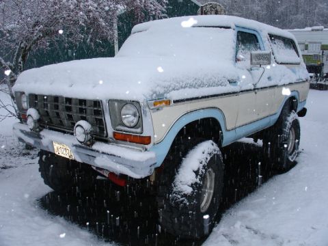 1978 Ford Bronco - This lifted 1978 Ford Bronco is covered in snow, showing its distinctive two-tone paint and off-road tires.