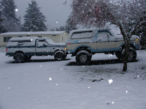 1978 Ford Bronco - A lifted 1978 Ford Bronco and a pickup truck sit parked in the snow during a March snowfall.