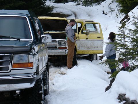 1978 Ford Bronco - Two people stand near a yellow 1978 Ford Bronco with its hood up, parked in a snowy, wooded area.