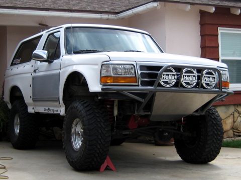 1996 Ford Bronco - A three-quarter front view of a white 1990s full-size Ford Bronco built as a prerunner, with a tubular front bumper mounting three Hella ro…