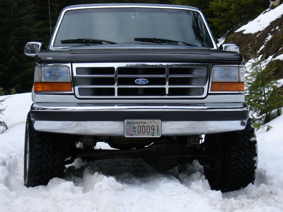 Front view of a lifted Ford F-150 truck in snow, with a chrome grille and Washington license plate