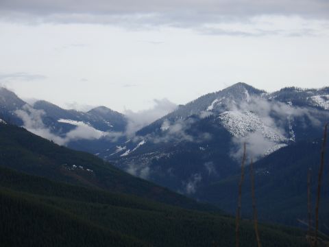 1978 Ford Bronco - A vast mountain landscape under a cloudy sky, with patches of snow on the peaks and trees covering the slopes.