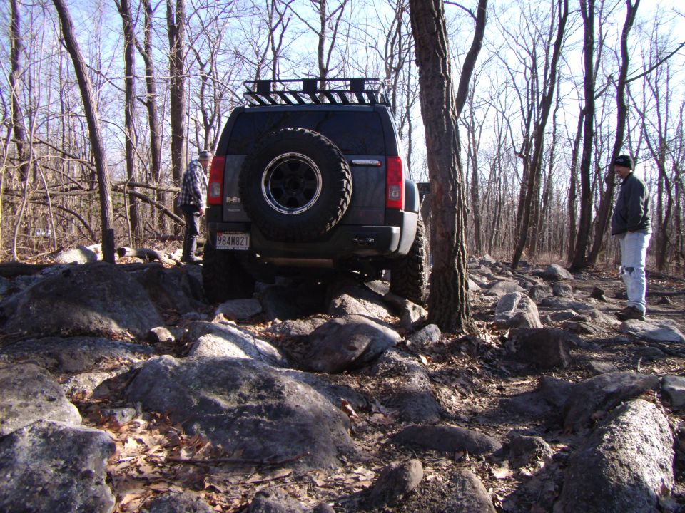 Dark SUV with spare tire on rear navigating rocky terrain