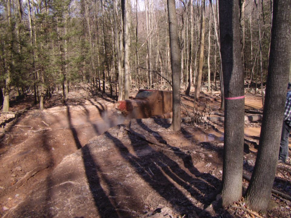 Brown off-road vehicle kicking up dust on a wooded trail
