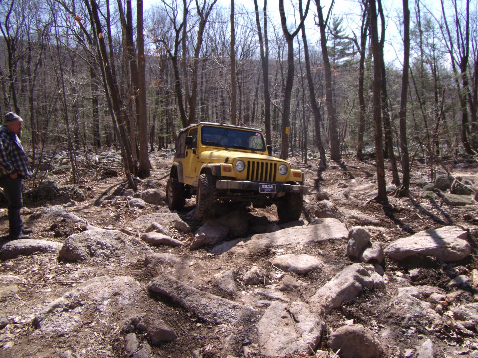 Yellow 2003 Jeep Wrangler navigating a rocky trail