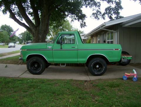 1979 Ford Bronco - A green pickup truck is parked in a driveway next to a house, with a tree overhead.