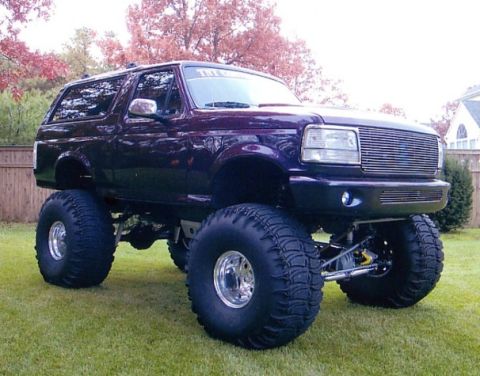 1994 Ford Bronco - This heavily modified Ford Bronco features oversized tires and a lifted suspension, with its grille suggesting a 1994 model year.