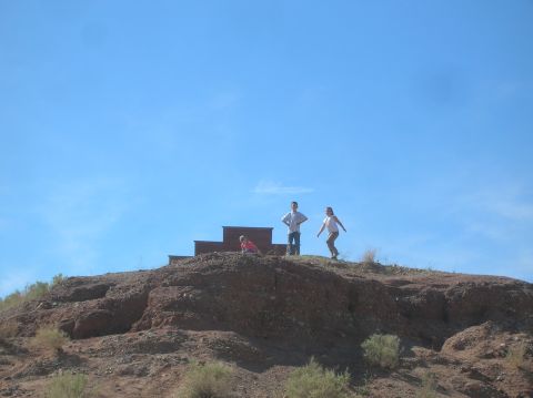 1985 Ford Bronco - People gather on a barren, rocky hilltop with a few sparse bushes.