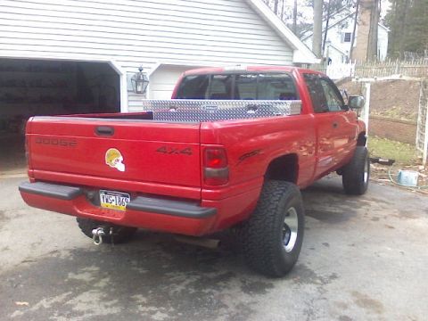 1997 Dodge 1500 - A red Dodge 1500 pickup truck is parked in a driveway next to a garage.