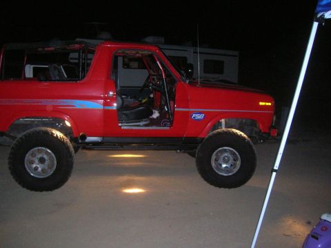 1985 Ford Bronco - This red SUV has a distinctive body style and large tires, suggesting an older model year.