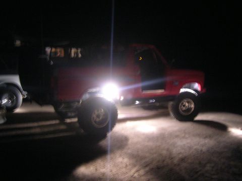 1985 Ford Bronco - A red truck is parked at night, its headlights illuminating the ground.