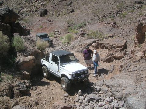 1985 Ford Bronco - Two vehicles traverse a , rocky canyon trail, highlighting their off-road capabilities.