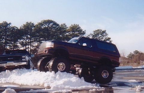 1994 Ford Bronco - A lifted 1994 Ford Bronco navigates through snow, its impressive off-road capabilities.