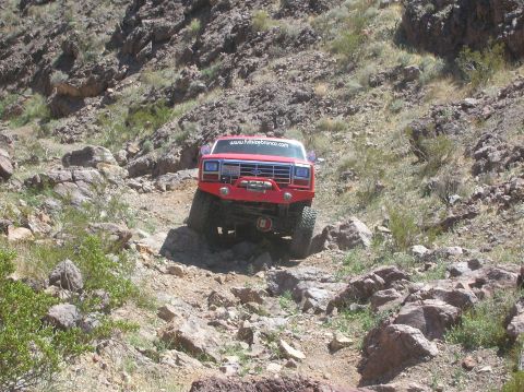 1985 Ford Bronco - This modified Ford Bronco navigates a challenging rocky trail, displaying the website www.furiousbronco.com on its windshield.