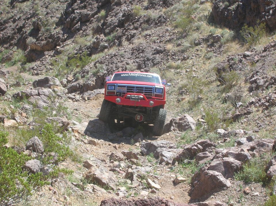 Red off-road Ford Bronco on rocky terrain with website www.furiousbronco.com on windshield