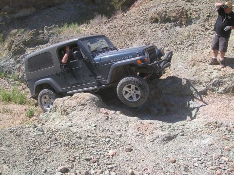 1985 Ford Bronco - A Jeep Wrangler Rubicon navigates a rocky incline, demonstrating its off-road capabilities.
