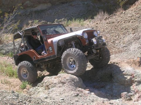 1985 Ford Bronco - This modified Jeep CJ-7 navigates a challenging rocky terrain during an off-road excursion.