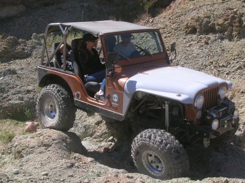 1985 Ford Bronco - A modified Jeep CJ-7 navigates a challenging, rocky off-road trail.
