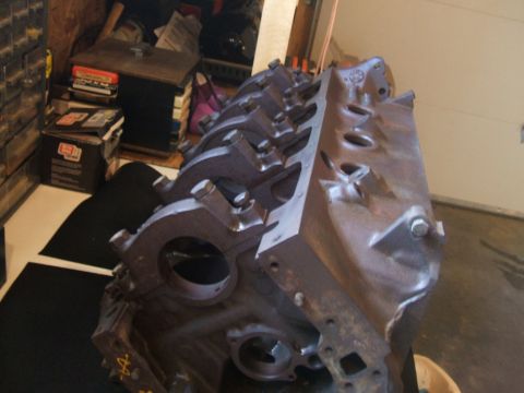 1974 Ford Ranchero - A close-up view of a cast iron engine block, likely for a V8 engine, sitting on a garage floor.