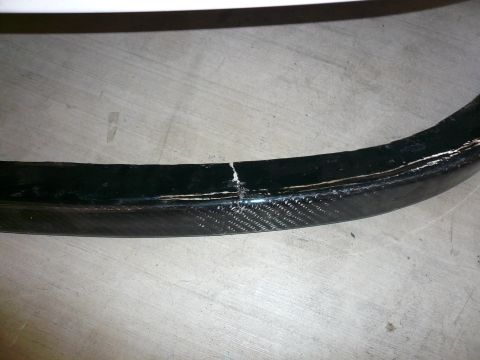 1996 Ford Probe - A damaged carbon fiber wheel rim shows a significant crack and signs of wear on its surface.