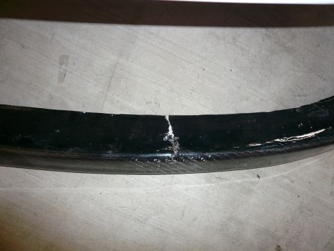 1996 Ford Probe - A damaged black trim piece is shown up close against a concrete surface.