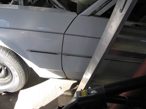 1991 Ford LTD Crown Victoria - Side view of a white car's fender and door, with a ladder in the foreground.