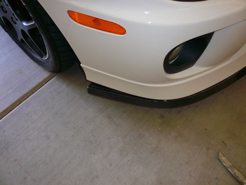 1996 Ford Probe - Close-up of a white car's front bumper, an aftermarket lip and an orange turn signal indicator.